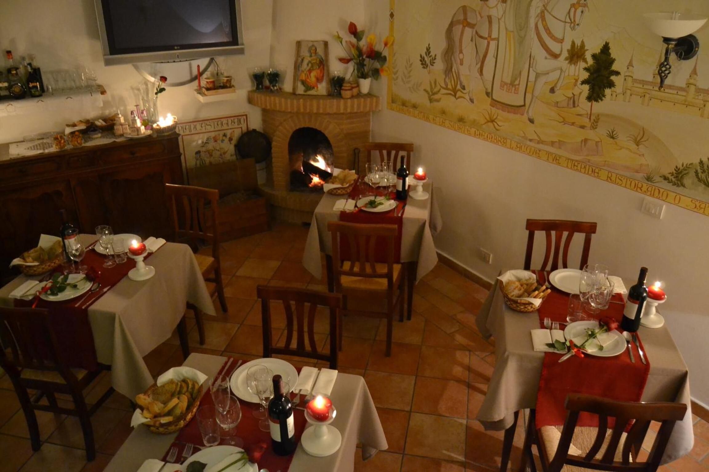 A dining area with tables set for meals, a fireplace, and a mural on the wall.