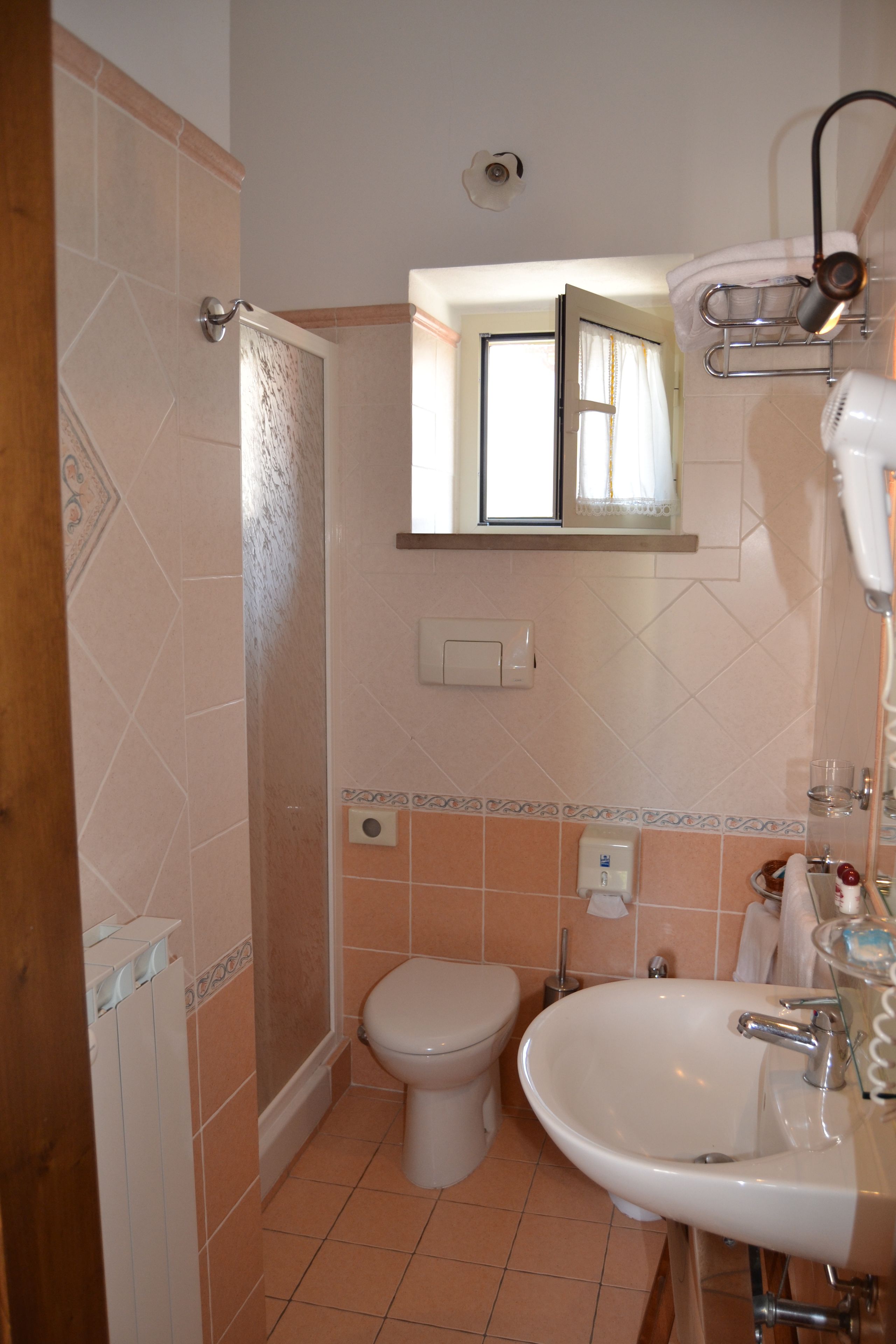 Une salle de bain équipée d’une douche, de toilettes, d’un lavabo et d’un miroir au-dessus du lavabo.