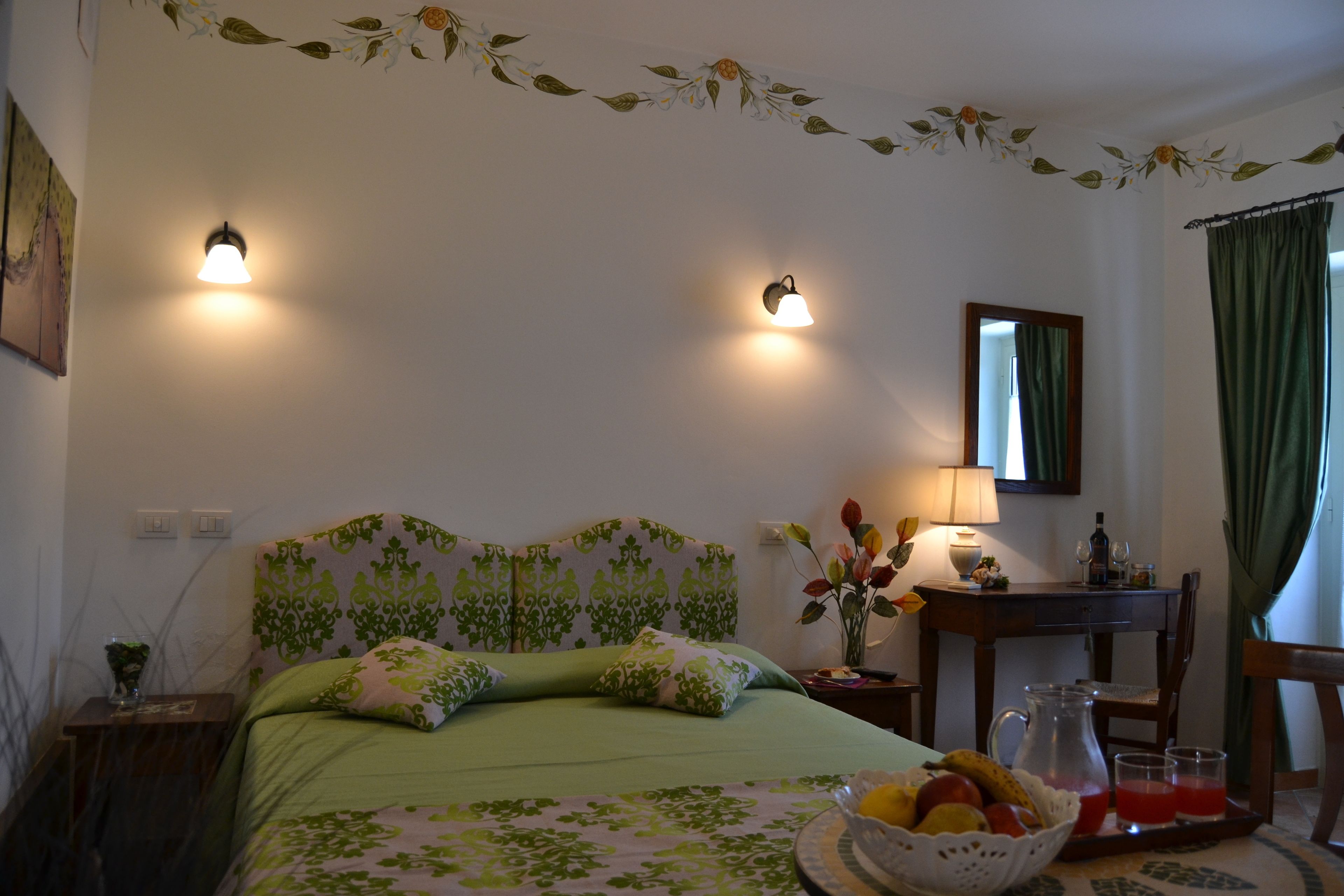 Un dormitorio con cama, mesita de noche, lámpara, espejo y un área de comedor con mesa y sillas.
