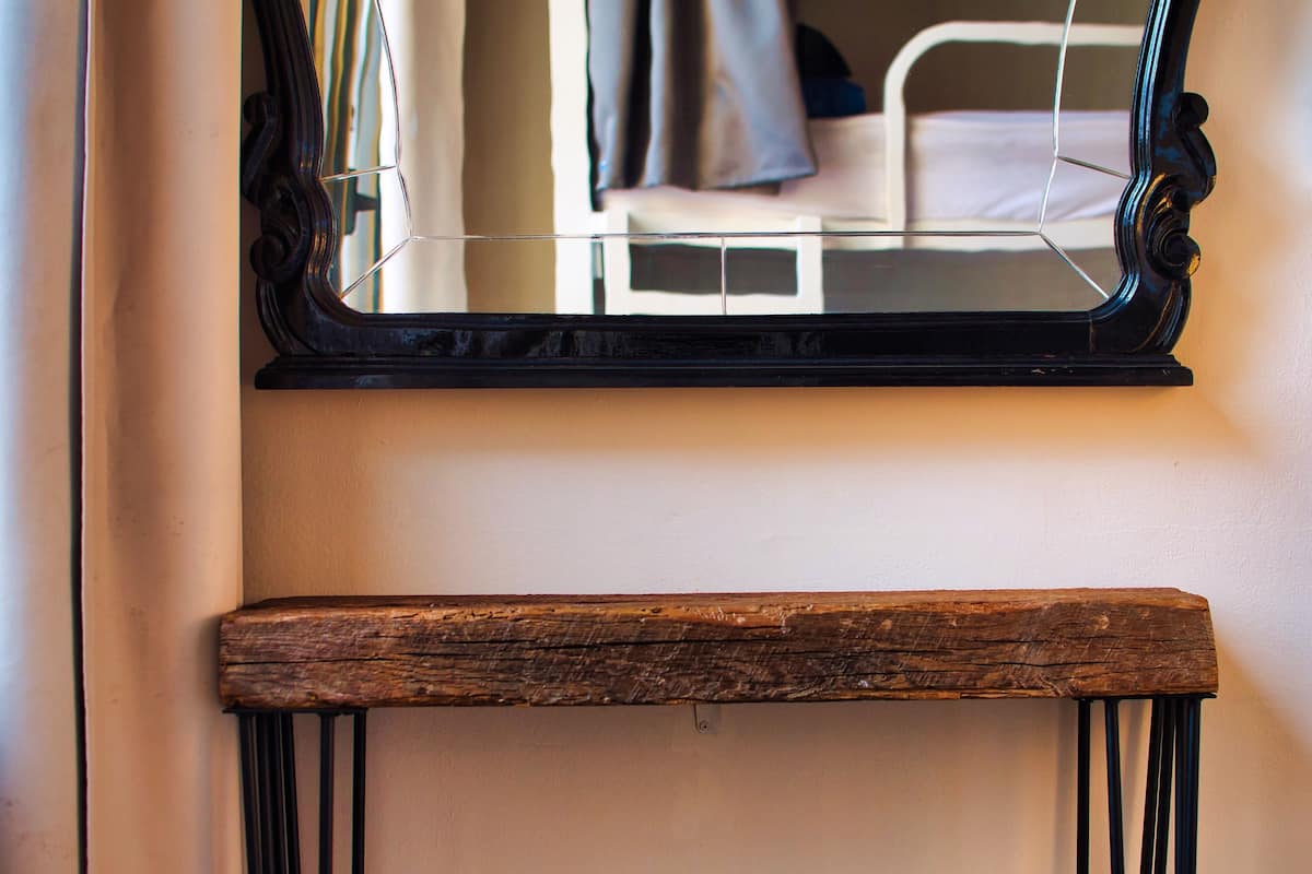 A mirror with a wooden frame and a wooden bench below it.