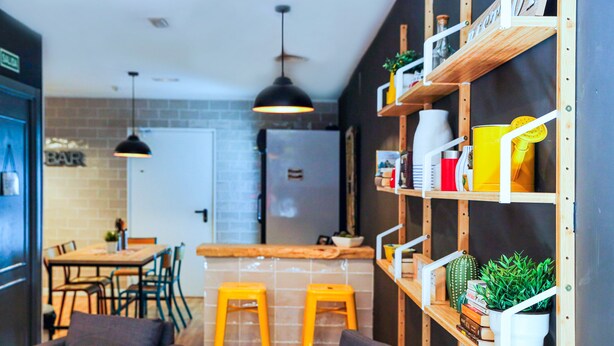 Una cocina moderna con protector mural de ladrillo, taburetes de bar de madera y una lámpara colgante.