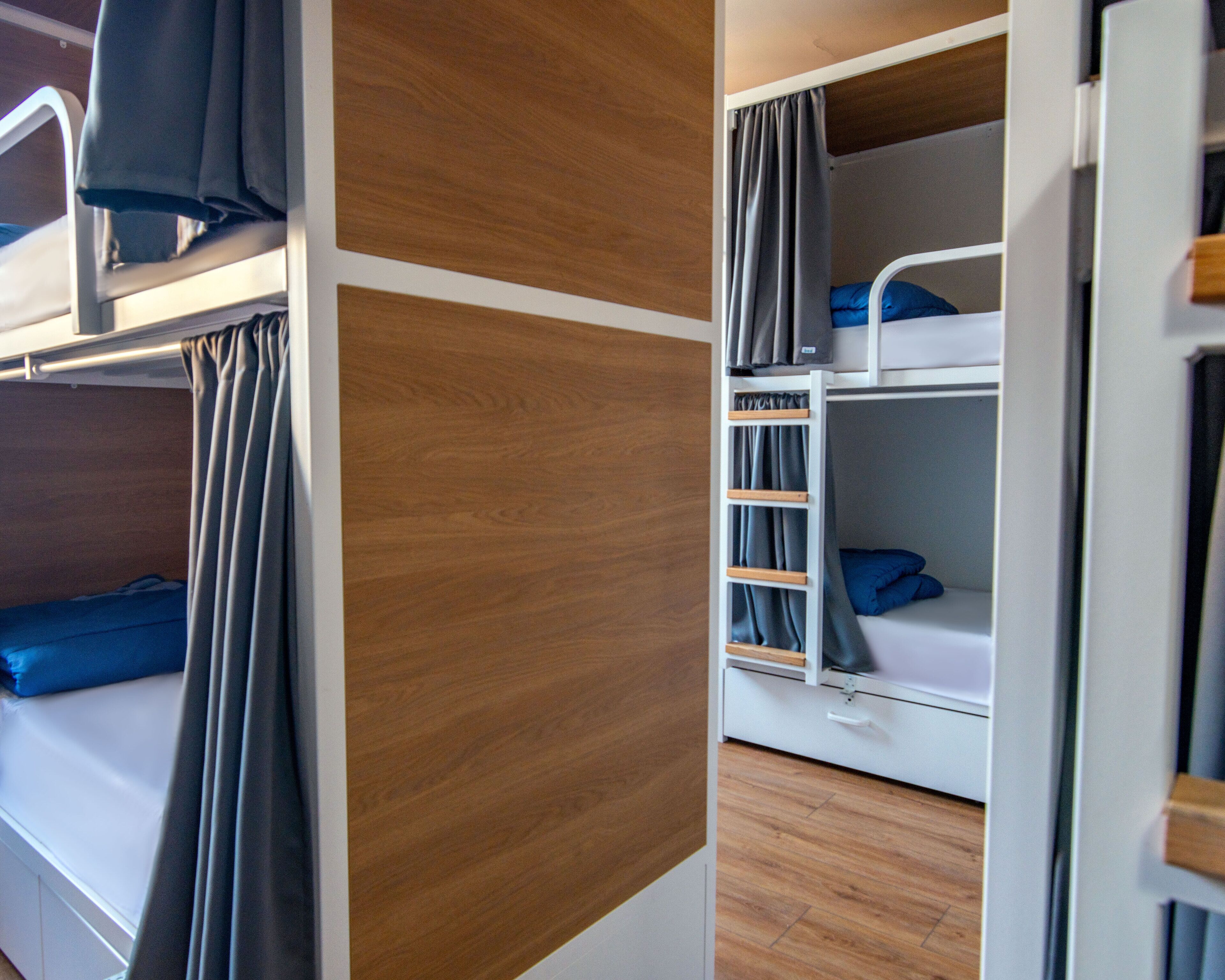 Habitación con literas, un panel de pared de madera, una escalera y un pequeño mueble con cajones.
