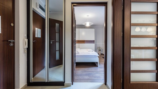 A hotel room with a bed, a bedside table, a nightstand, a wall-mounted TV, and a window. - Tatrytop Apartamenty Tetmajer (Zakopane)