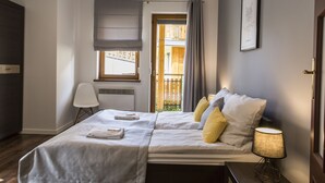 A neatly made bed with pillows, a bedside lamp, and a window with curtains.
