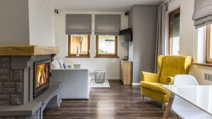 A modern living room with a fireplace, a sofa, a yellow armchair, and a dining table.