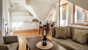 A modern kitchen with white cabinets, a dining area with a wooden table and chairs, and a cozy seating area with a sofa and a coffee table.
