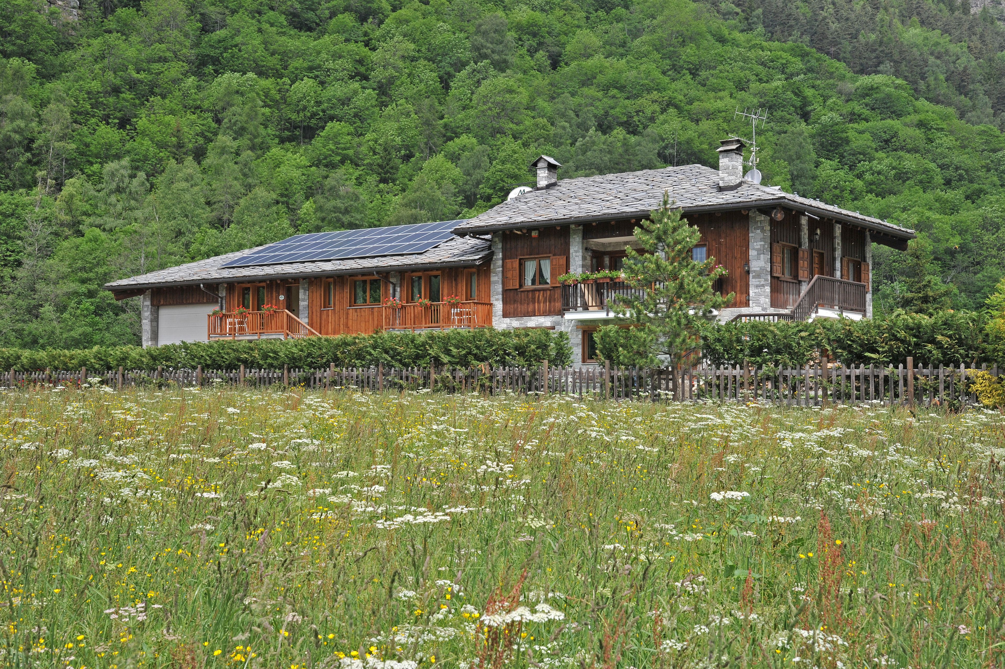 A rustic house with a stone facade, wooden shutters, and a sloped roof.