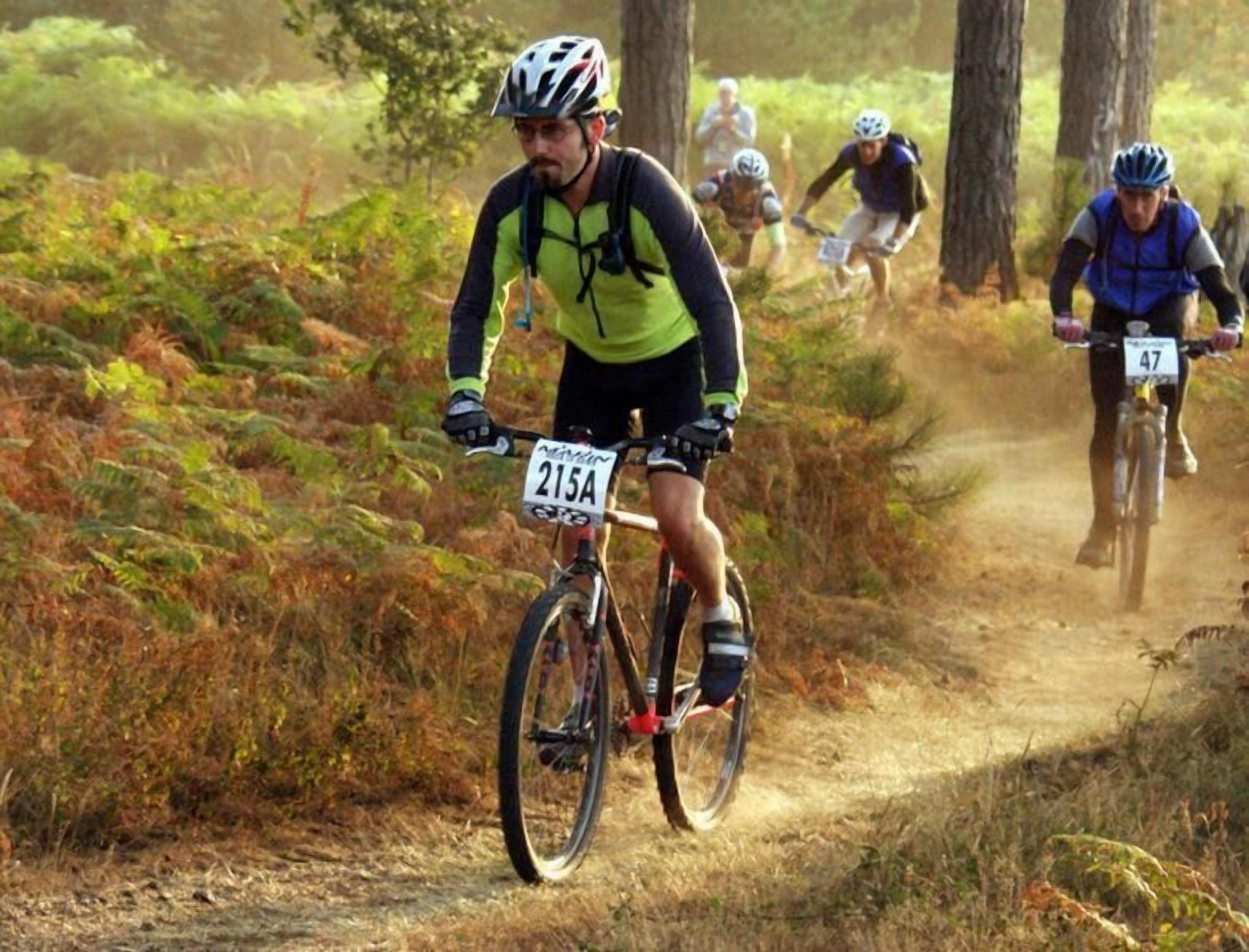 Un evento de ciclismo de montaña en un sendero de tierra rodeado de árboles.