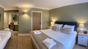 Habitación de hotel con dos camas, baño y televisor.