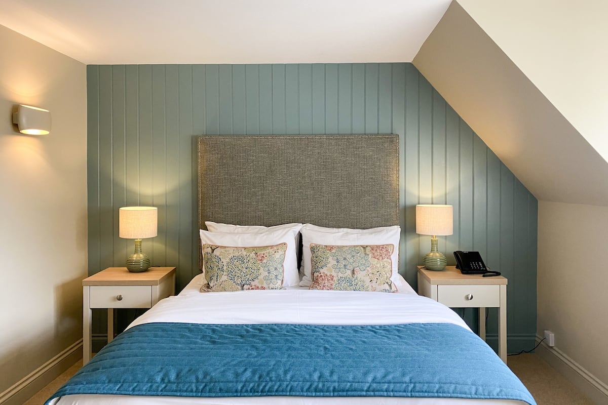 A bedroom with a bed, two bedside tables, a telephone, and a lamp on each table.