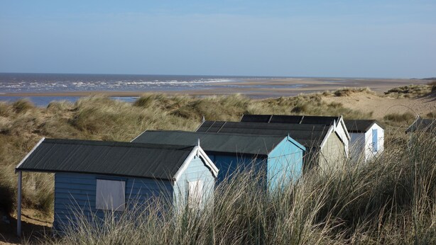 Una hilera de cabañas de playa con vistas al mar.
