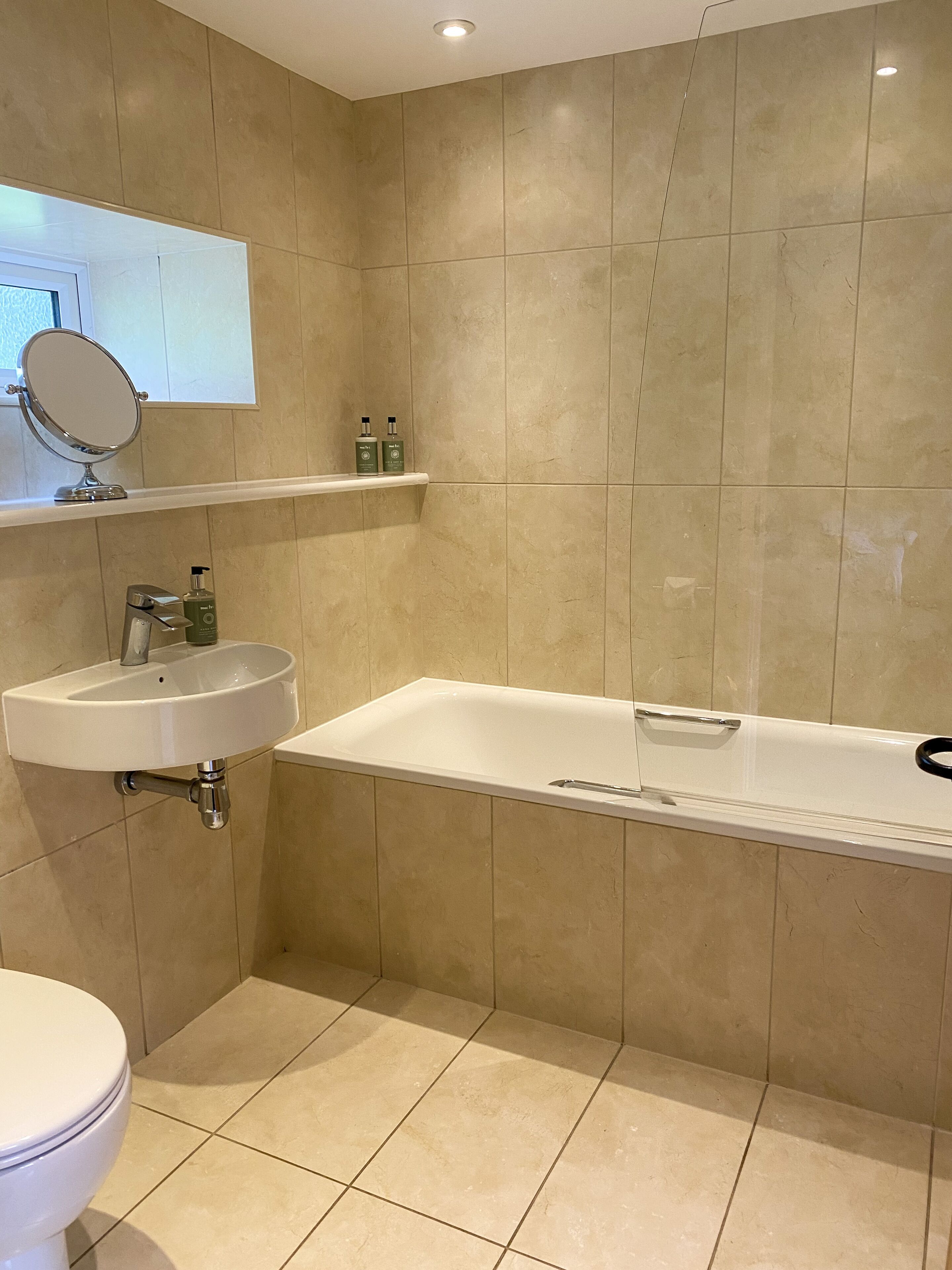Een badkamer met een wit wastafel, een spiegel en een bad.