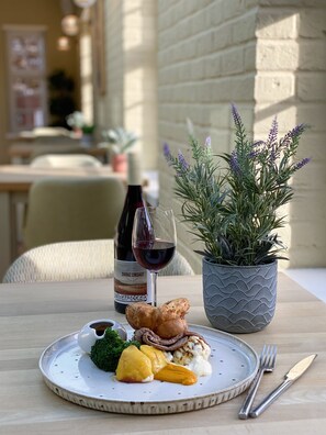 A dining table with a plate of food, a wine bottle, and a potted plant.