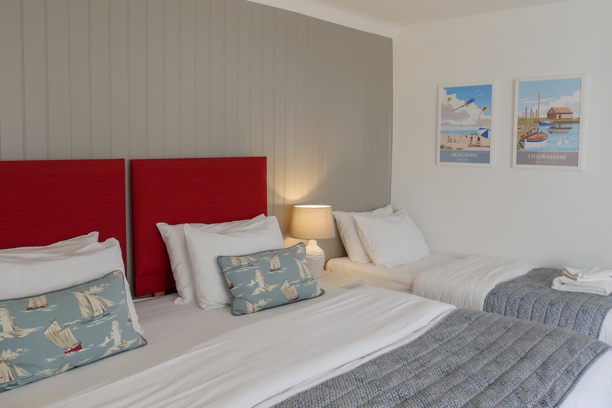 A hotel room with a large bed, two bedside tables, a lamp, and two framed pictures on the wall.