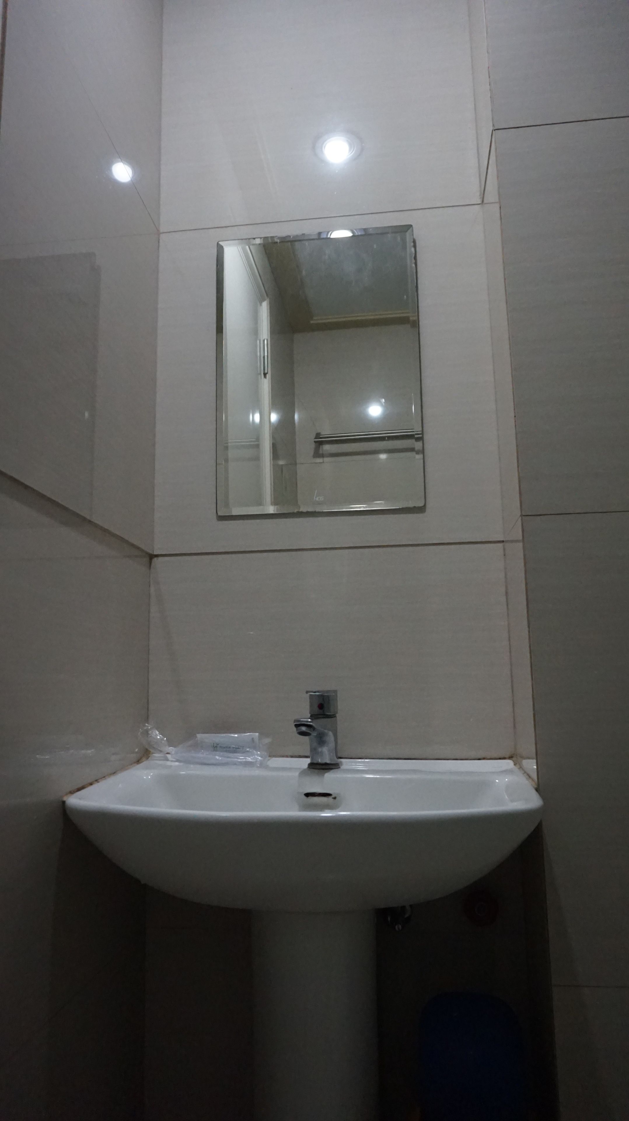 A bathroom with a white sink, a mirror above it, and a light fixture on the ceiling.
