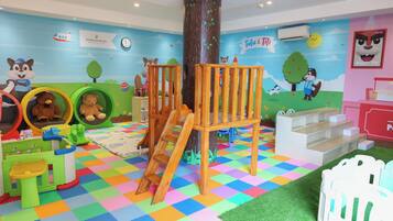 A children's play area with a colorful checkered floor, play structures, and educational murals.