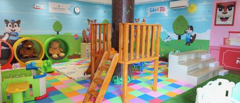 A children's play area with a colorful checkered floor, play structures, and educational murals.