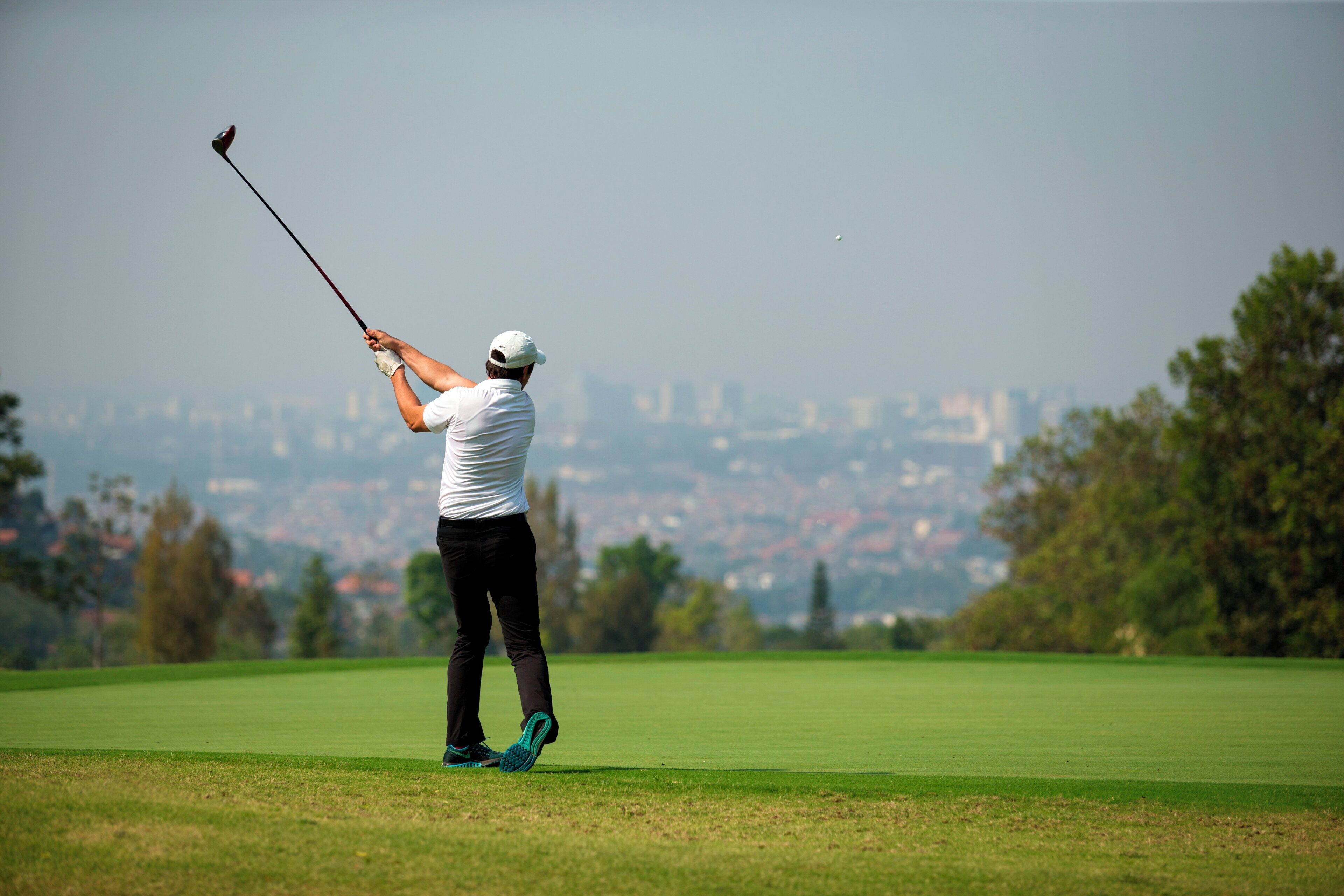 A golfer on a green with a city skyline in the background.