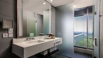 A modern bathroom with a large mirror, two sinks, and a glass shower enclosure.