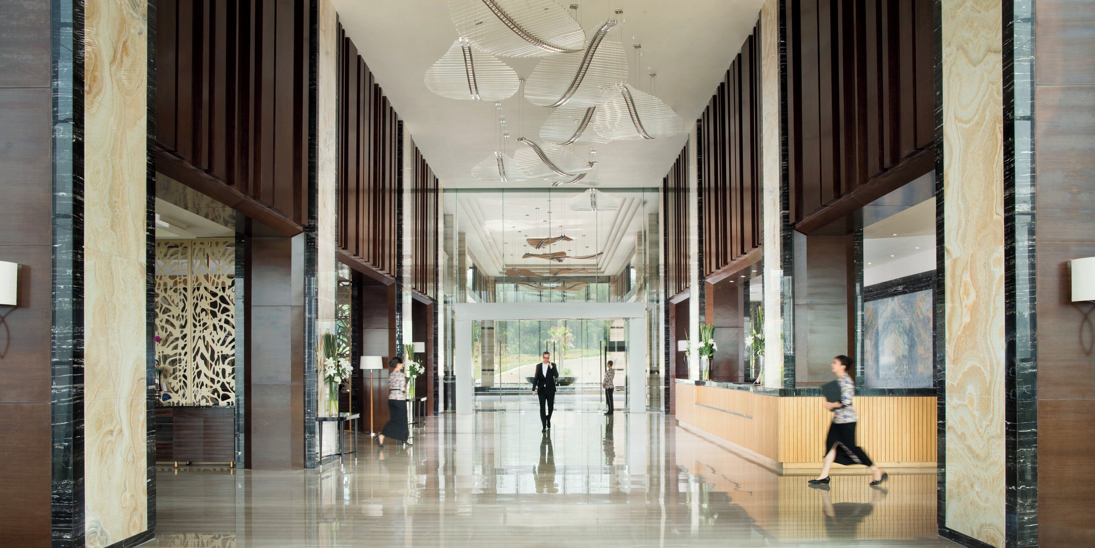 A spacious lobby with a high ceiling, modern lighting fixtures, and a reception desk.