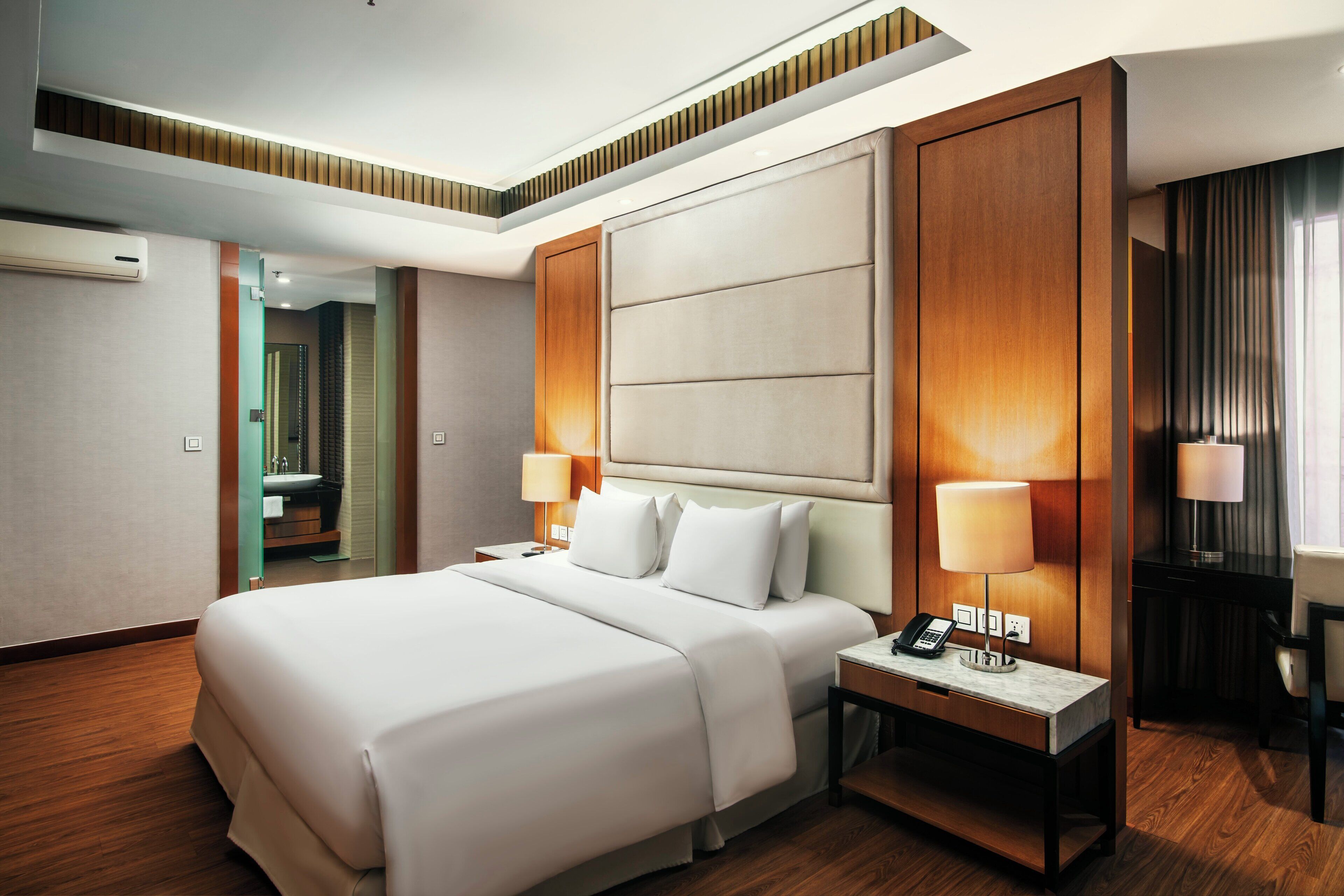 Une chambre d’hôtel avec un grand lit, des lampes de chevet, un bureau avec un téléphone et une vue sur la salle de bain.