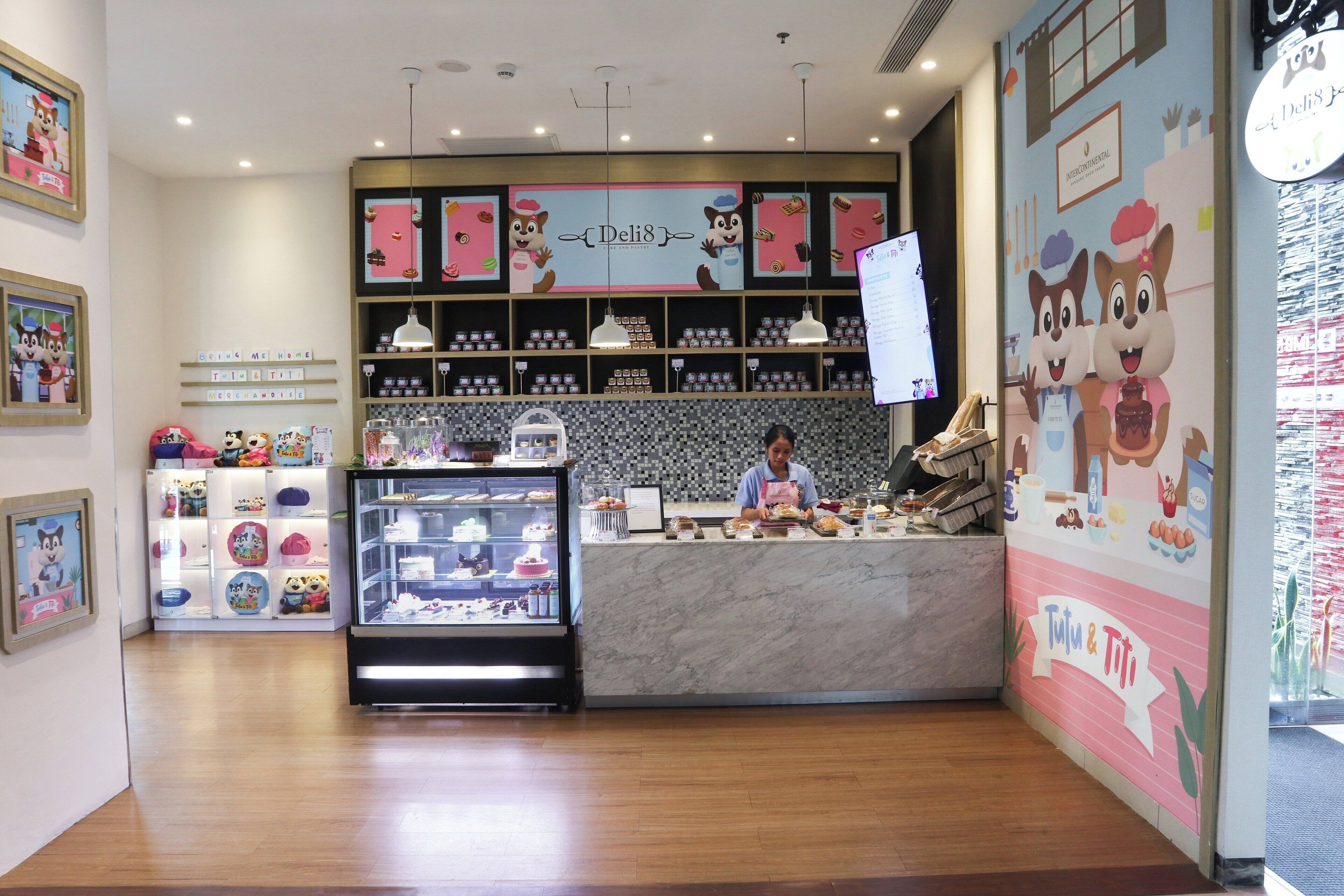 Un comptoir de charcuterie avec un plan de travail en marbre, des étagères remplies de produits alimentaires et une vitrine où sont exposées des pâtisseries.