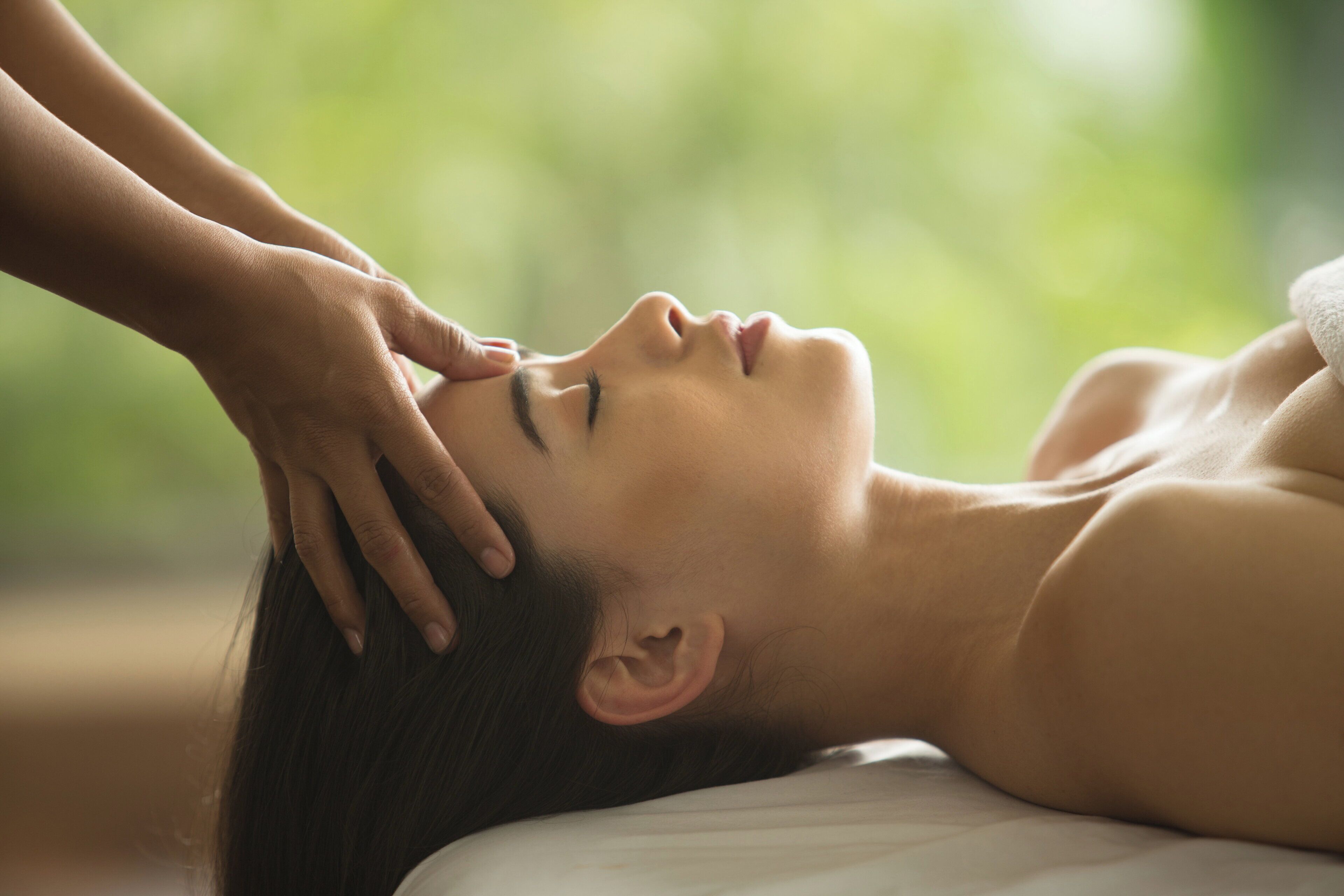 Una persona acostada con la mano en la cabeza, sugiriendo un ambiente de spa o relajación.