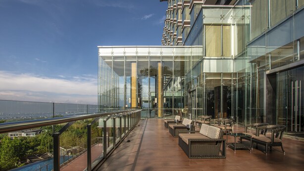 A modern outdoor lounge area with glass walls, wooden flooring, and outdoor seating. - InterContinental Bandung Dago Pakar by IHG (Cimenyan)