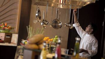 Un chef alcanzando una olla de un colgador en una cocina.