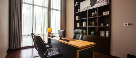 A modern office with a wooden desk, black office chair, and a large bookshelf.