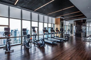 A modern gym with treadmills, elliptical machines, and weight equipment, large windows with a city view, and a polished wooden floor. - Wyndham Grand Shenzhen (Shenzhen)