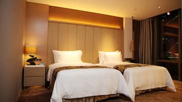 A hotel room with two beds, a nightstand, and a lamp.