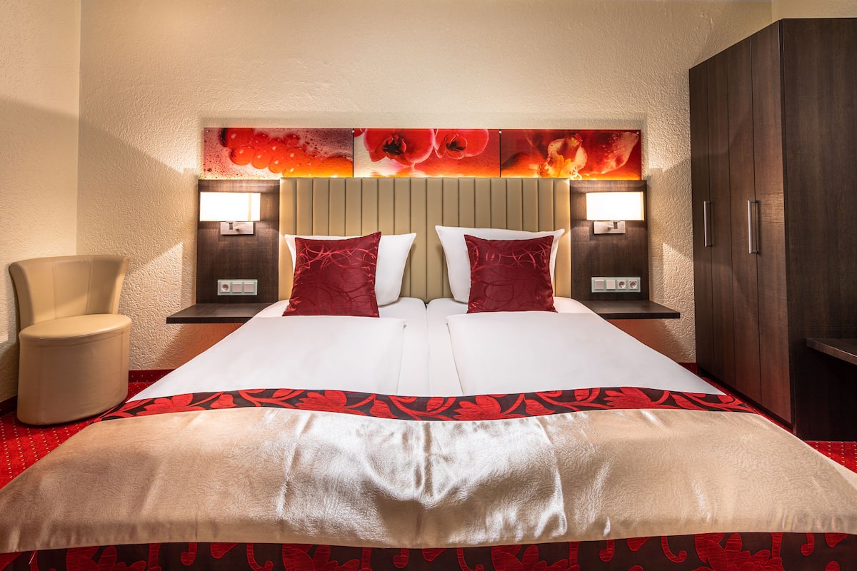 Habitación de hotel con una cama grande, dos mesitas de noche con lámparas, una silla y un armario.
