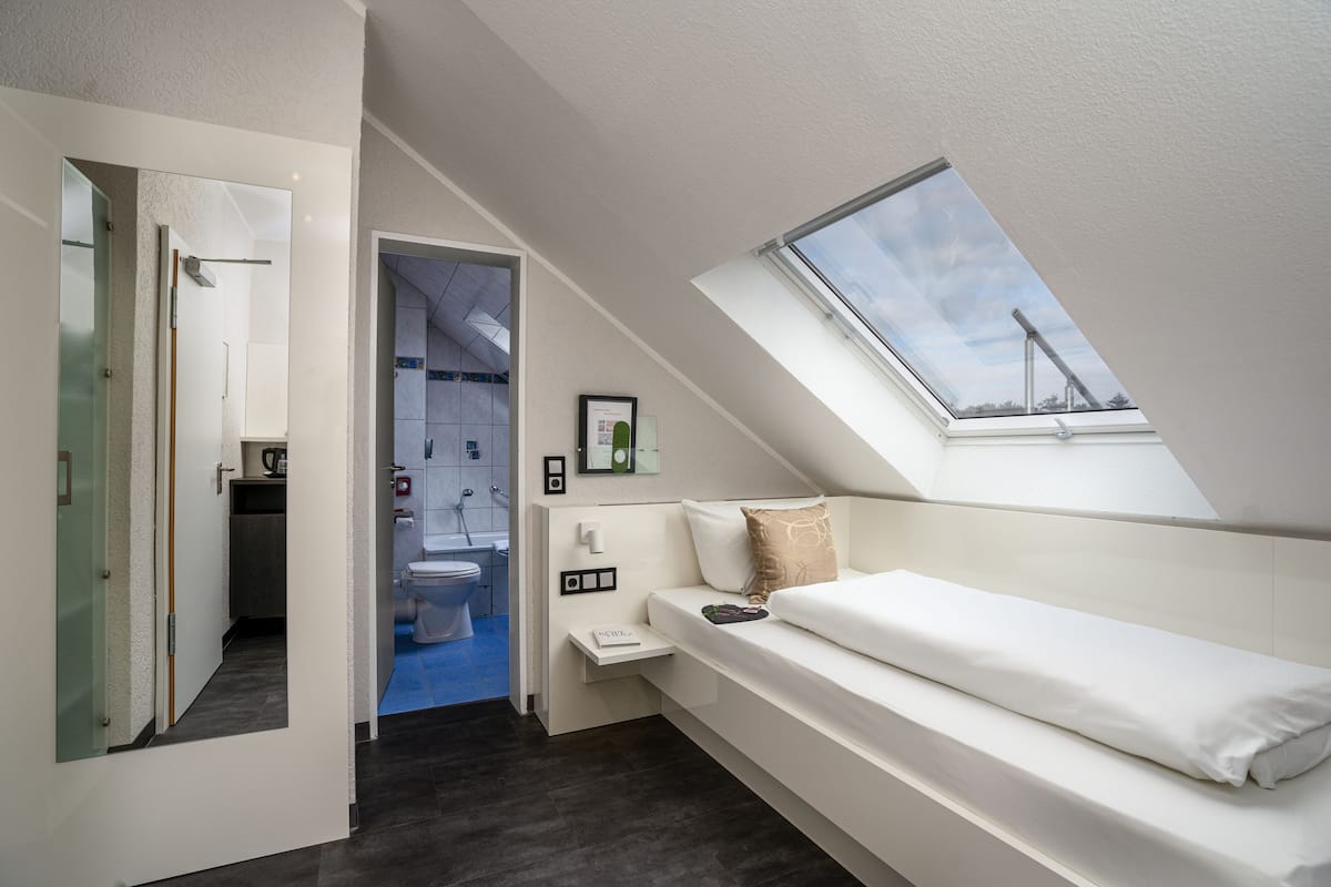 Un dormitorio moderno con tragaluz, un banco empotrado y vista al baño.