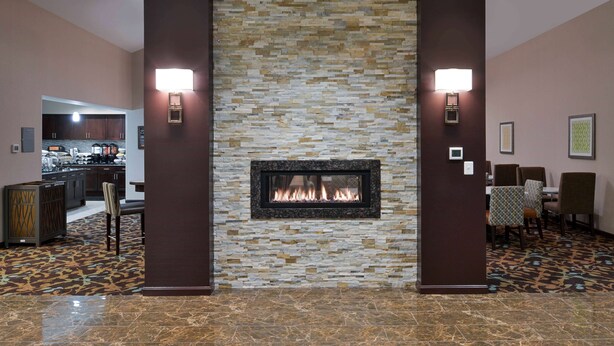 A lobby with a stone wall fireplace, seating area, and a bar. - Homewood Columbia Laurel (Laurel)