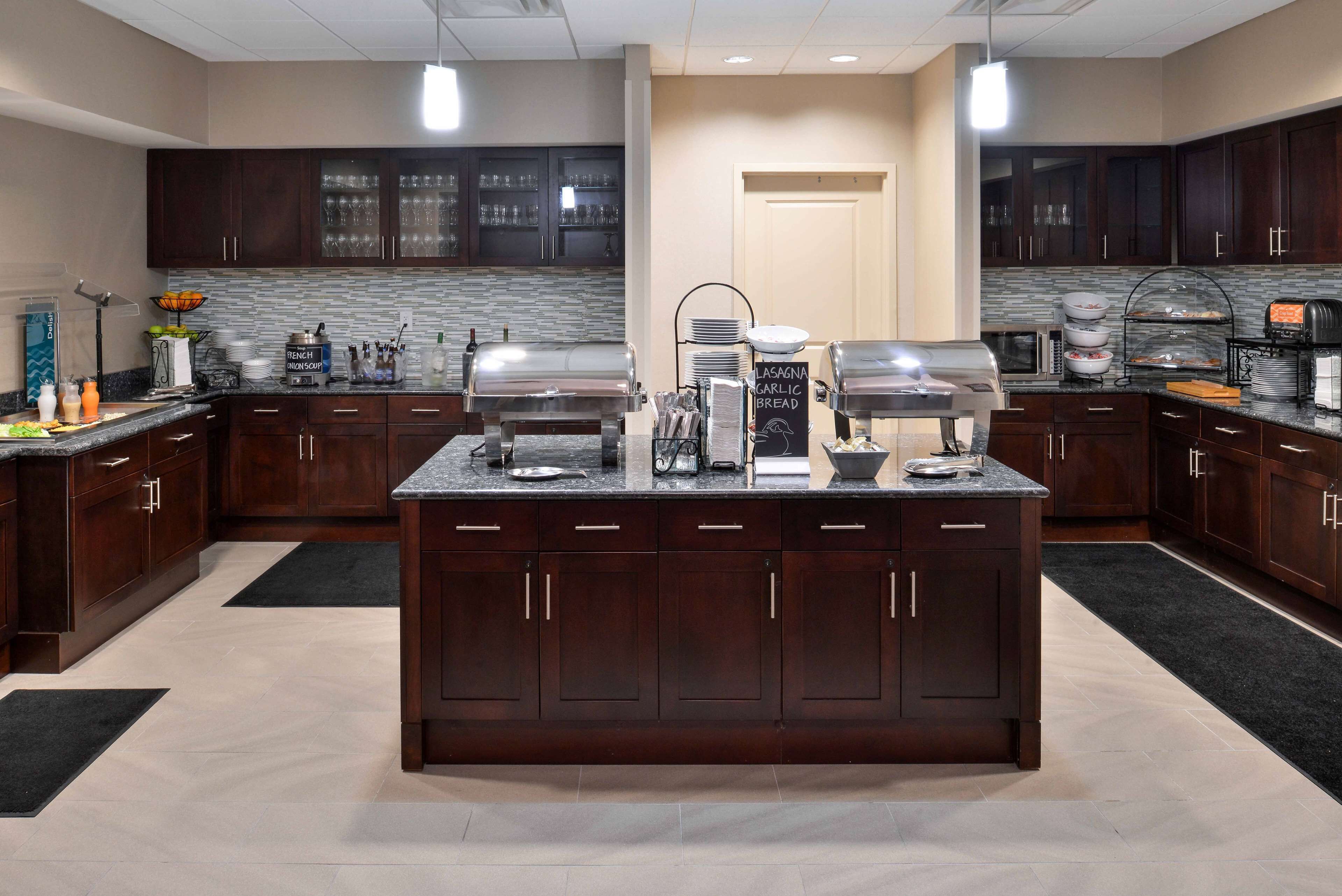 Una cocina moderna con alacenas de madera oscura, una isla central con estación de café y un salpicadero de azulejos.