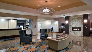 A lobby with a reception desk, seating area, and a stone fireplace. - Homewood Columbia Laurel (Laurel)