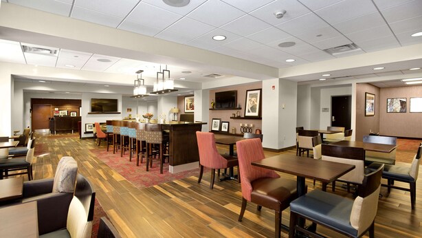 A spacious hotel lobby with multiple seating areas, a reception desk, and a television mounted on the wall. - Hampton Inn Butler (Butler)