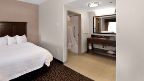 A hotel room with a bed, a bathroom with a sink and mirror, and a shower. - Hampton Inn Butler (Butler)