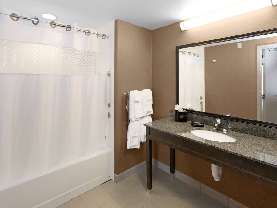 A bathroom with a shower, a sink, a mirror, and a towel rack.