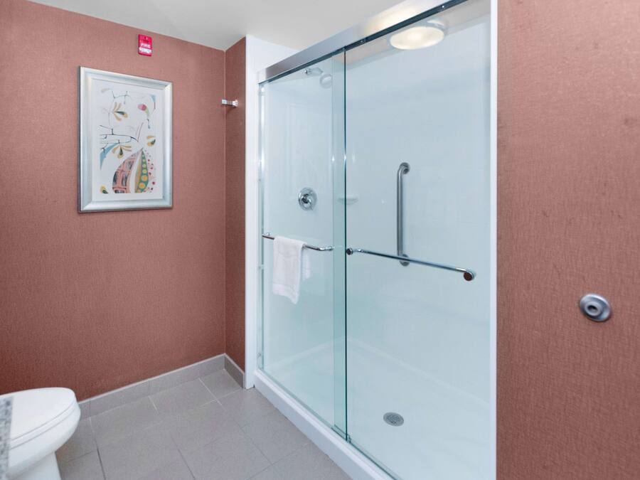 A bathroom with a glass shower enclosure, a toilet, and a framed artwork on the wall.