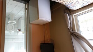 Un baño con inodoro, espejo y televisor.