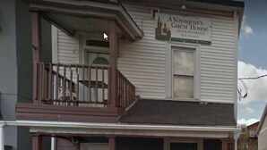 Un edificio de dos pisos con un letrero que dice 'A Voyageur's Guest House', ofreciendo alojamiento y desayuno.