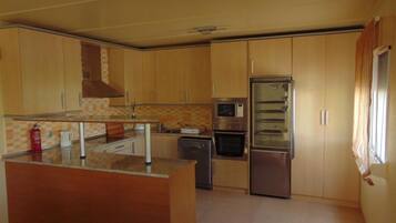 Una cocina compacta con armarios de madera, microondas, horno integrado y refrigerador.