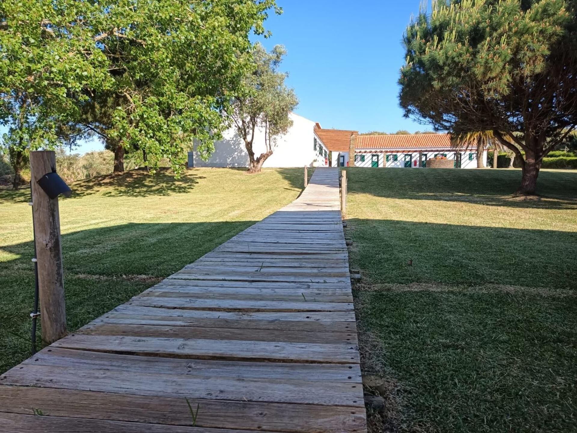 Un sendero de madera que conduce a un edificio con techo de tejas rojas.
