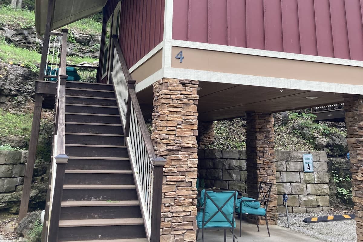 A two-story building with a stone foundation, a covered outdoor area, and a staircase leading to the upper level.