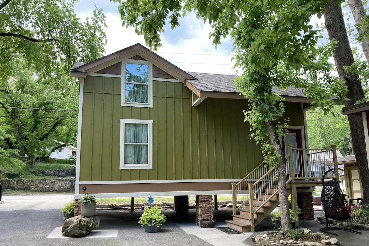 A two-story building with a green exterior, a front porch, and a staircase leading to a deck.