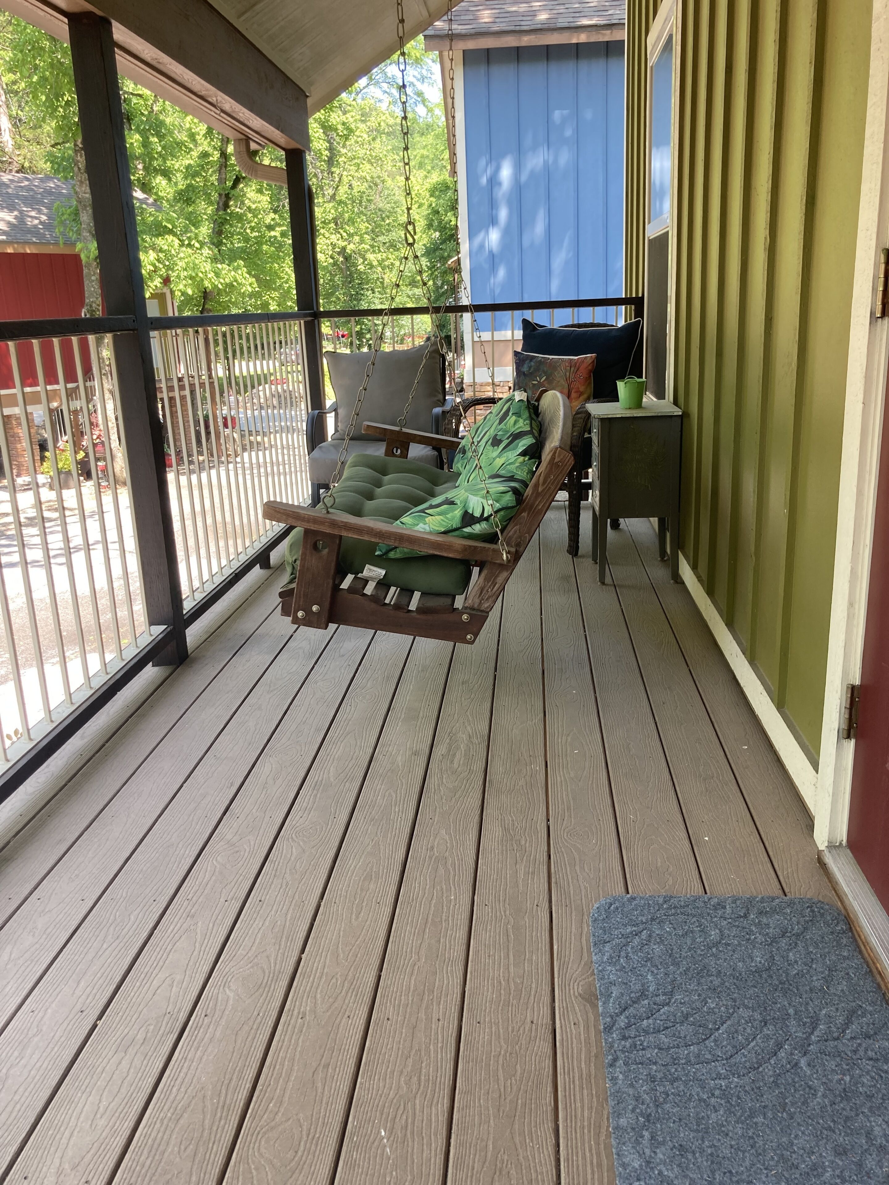 A wooden deck with a hanging chair and a small table.