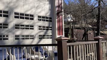 Una casa con un garage, un patio recintato con mobili in vimini e un portico in legno.