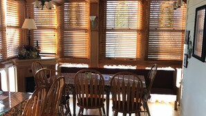 A wooden interior with a dining area, ceiling fans, and large windows with blinds. - All Seasons Inn (Eureka Springs)